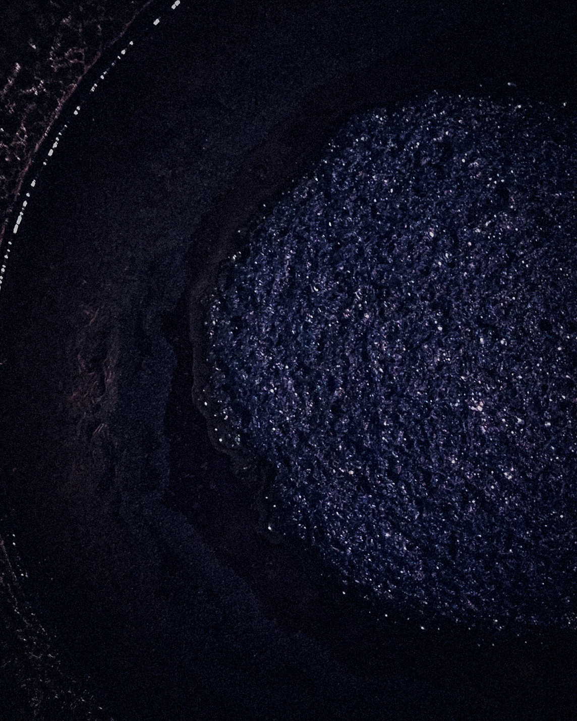 Surface of fermented sukumo indigo glistening deep blue inside the vat
