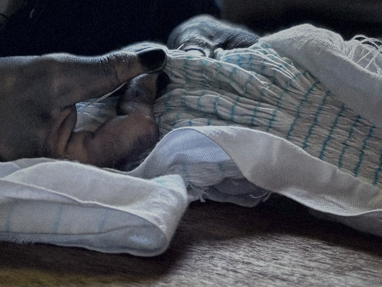 Indigo-stained hands and shibori-stitched cloth